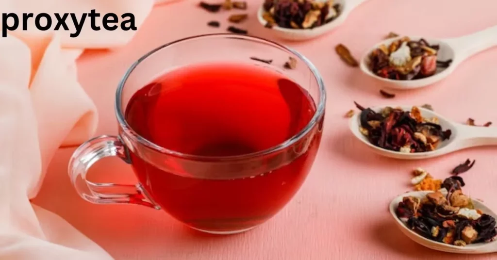 a glass cup of red liquid next to spoons of dried herbs